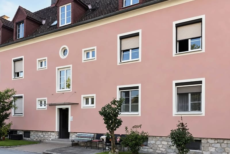 Dasselbe Mehrparteienhaus nach der Reinigung, der rosa Putz gleichmäßig hell